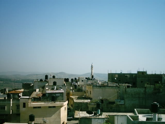 صورة لقرية يعبد - فلسطين: : مئذنة المسجد الكبير في وسط البلد وخلفها جبال قرية فحمة صورة مأخوذة من الحارة الشمالية في صيف عام 2005